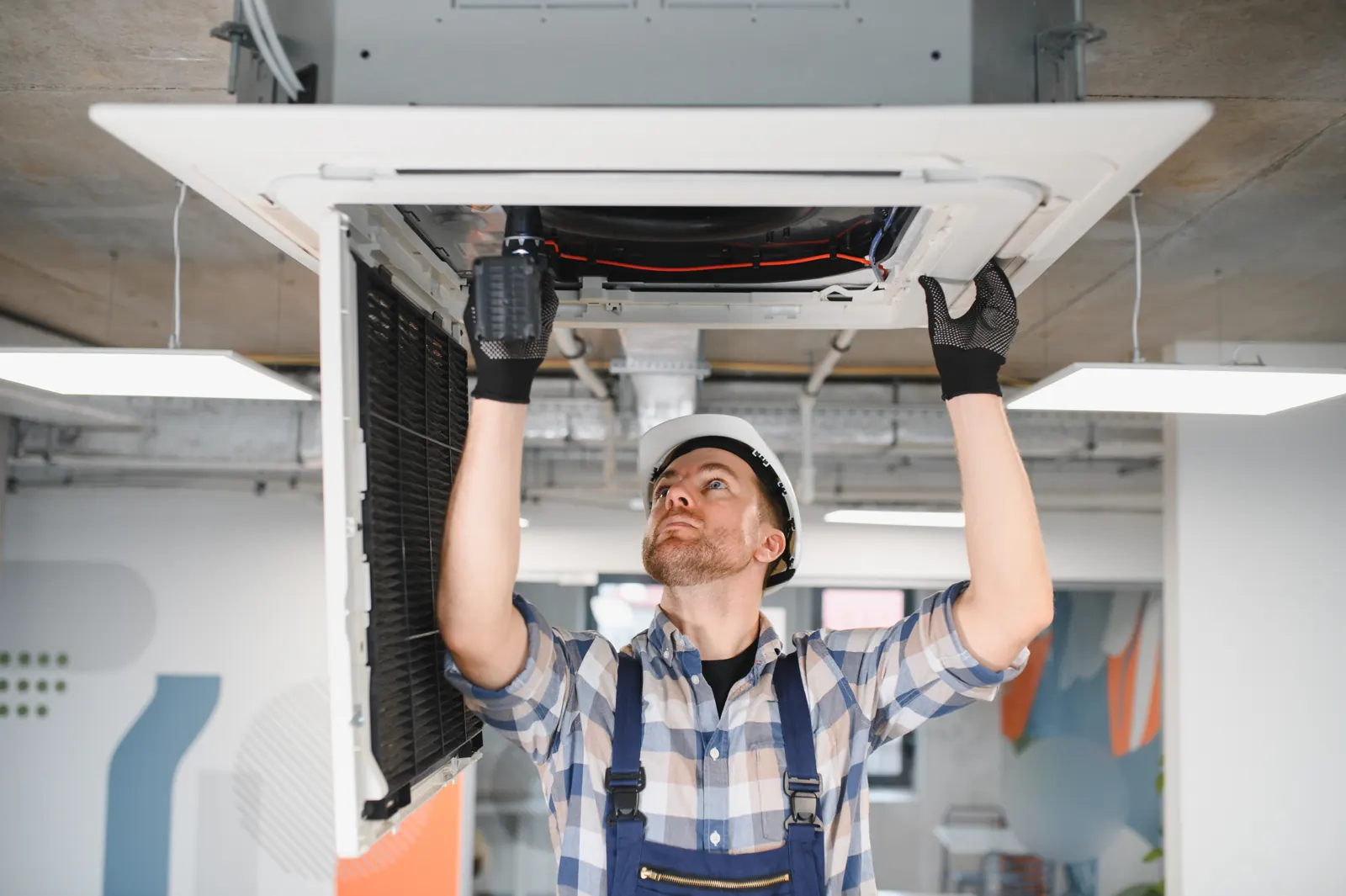 Technicien installant une cassette de climatisation au plafond